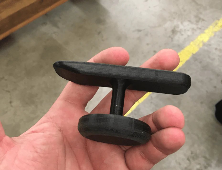 The first Ttool prototype, 3D-printed in black, held in an open hand